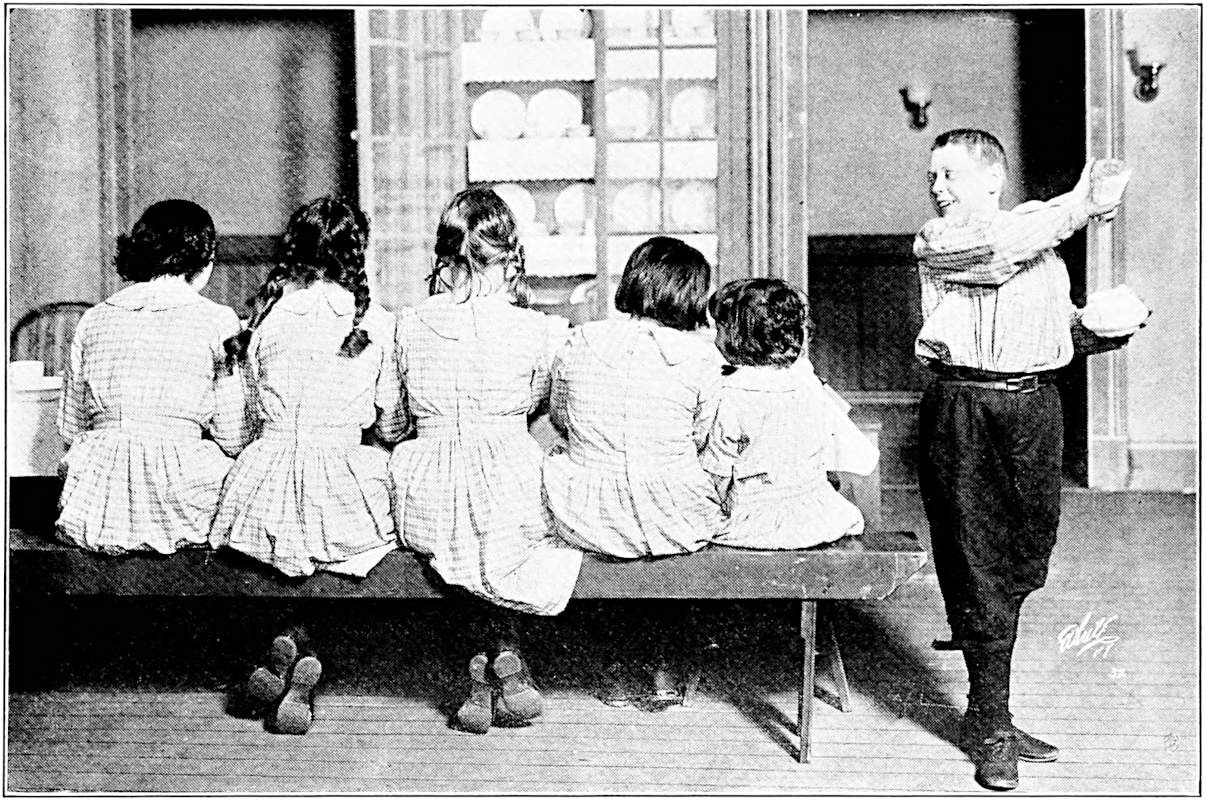 The girls sit at the table, their backs turned, as Freddie pours salt into the sugar bowl.